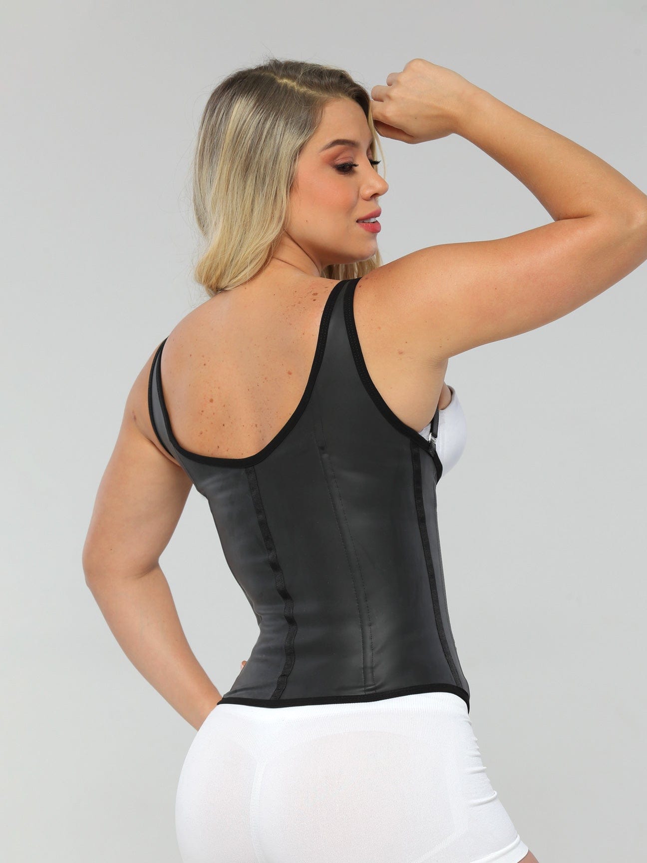 Back view of a model wearing the black semi vest latex waist trainer.