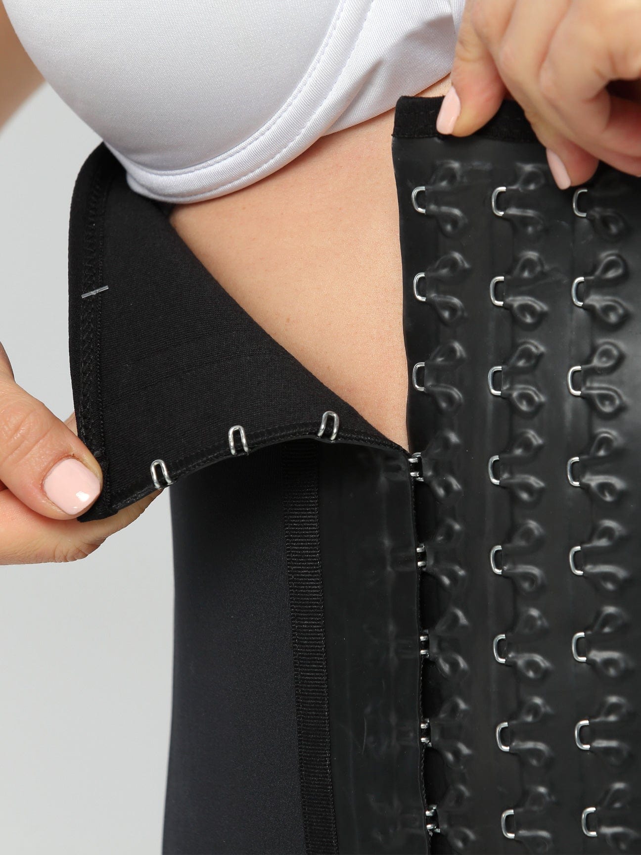 Black Colombian latex waist trainer with adjustable hook-and-eye closure, close-up